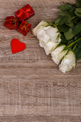White roses with heart on wood background. Love design. 8 march concept. Fresh natural flowers with gift boxes. Wooden rustic board.