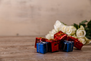 White roses with gift boxes on wood background. Love design. Valentines day or 8 march concept. Fresh natural flowers. Wooden rustic board.