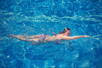 Woman in bikini swims in the pool