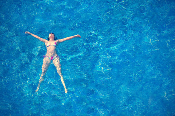 Woman in bikini and sunglasses lying in the water