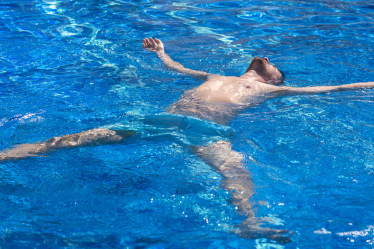 Man in blue shorts lying on the water