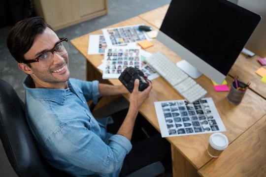 Man sitting at desk holding digital camera