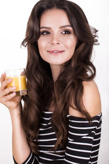 Beautiful woman with healthy skin, hair curls and orange juice posing in studio. Beauty face
