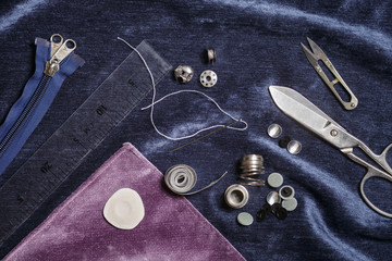 Sewing accessories on a blue fabric background. Top view.