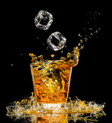 Glass of whiskey with splash on black background