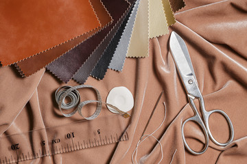 Composition of crafting tools and sewing accessories on a fabric background. Top view.