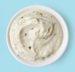 Garlic sauce  in round dish on blue background