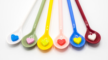 Multi color spoons with small heart shape on white background