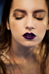 Close up portrait of beautiful woman with creative gold make up