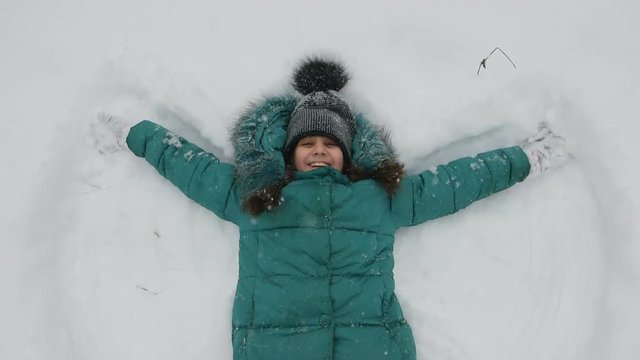 Child girl playing with snow in winter outdoors