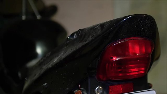Mechanic removes plastic back tail of black motorcycle in workshop