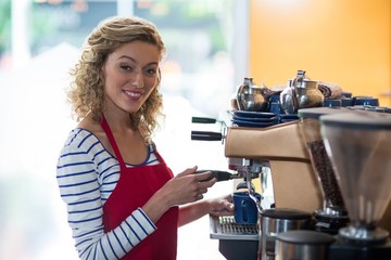 Portrait of smiling waitress making cup of coffee