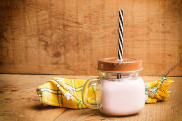 Vaso de Yogurt de fresa con pajita sobre mesa de madera rústica. Vista de frente. Copy space