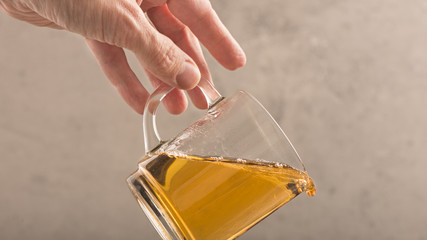 Hand of man drops tea cup. Hot drink falling. Concept of accident, mishap and danger.