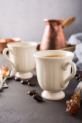 Two retro cups of coffee and old coffee pot on dark brown background with copy space.