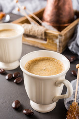 Two retro cups of coffee and old coffee pot on dark brown background with copy space.