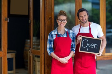  waitress and waiter standing with open sign board