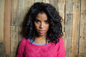 Portrait of woman standing against wooden wall