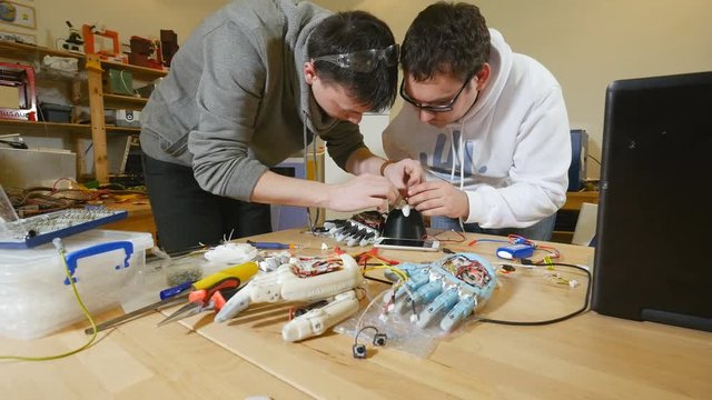 Two young engineers creating innovative cybernetic bionic arm. Hi-tech innovative technology. 4K.