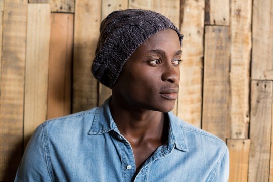 Thoughtful Man Standing Against Wooden Wall