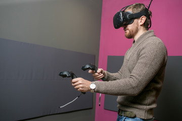 bearded man using the virtual reality headset and two controller