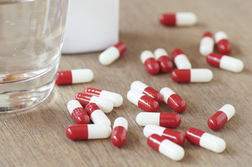 capsule and glass of water on wood table