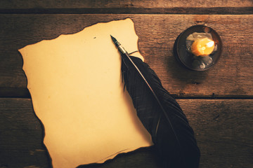 vintage feather pen and blank old paper in candlelight on the table