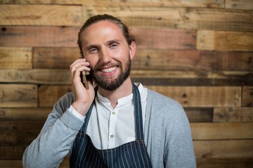 waiter talking on phone against wooden wall