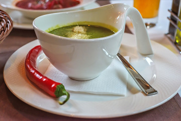 Spinach cream soup with chili in a white bowl