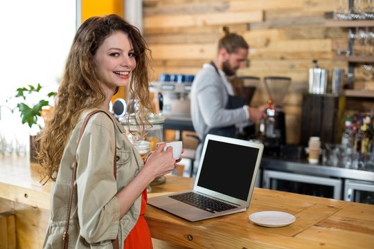 Woman standing at counter and using laptop