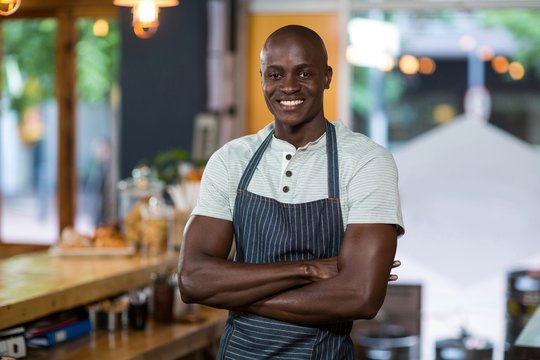 Smiling waiter standing at counter in café