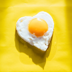 heart egg and yolk on yellow background- minimal trendy food the