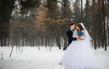 Fototapeta na wymiar Young stylish wedding couple at forest on winter day. Loving new
