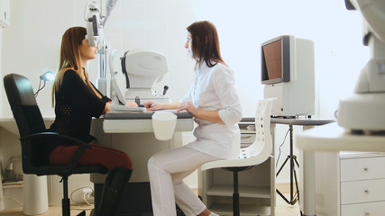 Modern ophthalmologist examining attractive woman's eyes with modern equipment