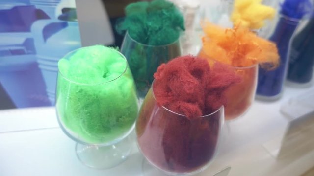 Samples of different colors plastic fibers produced using the extrusion in industrial equipment. Closeup. Shot in motion. Shallow depth of field