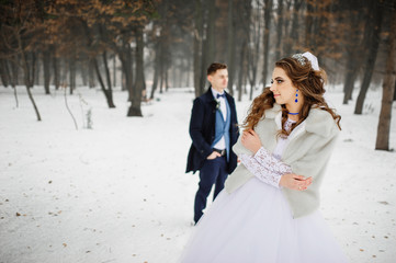Young stylish wedding couple at forest on winter day. Loving new