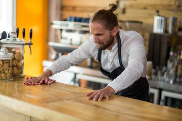 Waiter wiping counter with napkin in café