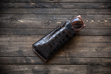 fashionable glasses with a leather holster on wooden background close-up