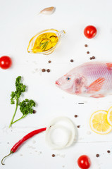 fresh tilapia on white wooden textured background with fresh ros