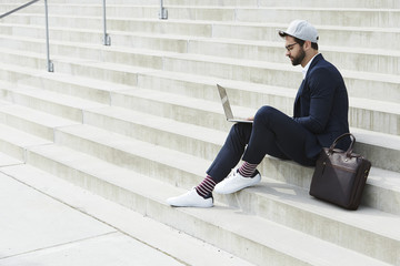 Hipster business dude working on laptop on steps