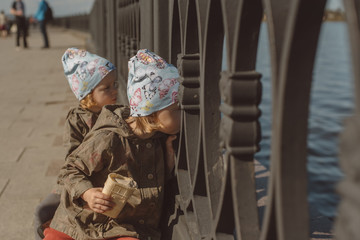 Two little girls on the river in the spring to eat ice cream