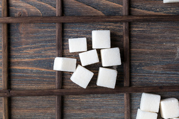White sugar cubes stacked on wooden desk. Top view. Selective fo