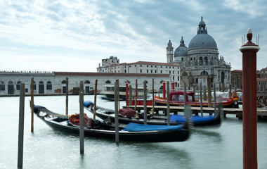 Fototapeta na wymiar Gondolas on the Grand Canal in Venice with the Santa Mana Della Salute and blue cloudy sky in the background.
