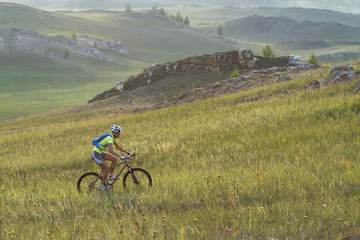 cycling in the mountains, a young girl athlete, mountain biking