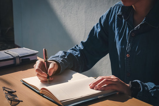 Male Hand Writing In Notebook With Pen In Home