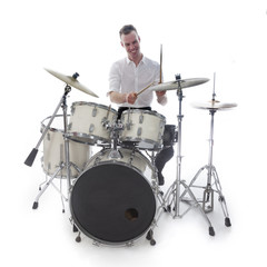 drummer behind drum set wears white shirt and plays the drums