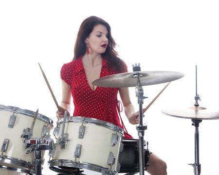 sexy brunette in red dress plays drum kit in studio