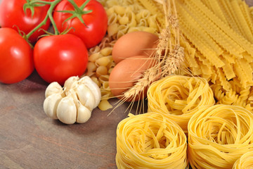 Uncooked Italian pasta, ripe tomatoes branch, garlic and eggs