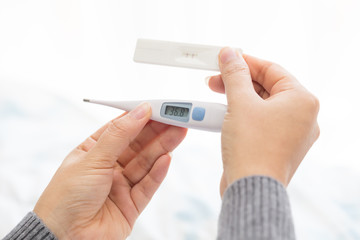 Woman hand holding thermometer and pregnant test