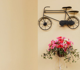 Fototapeta na wymiar Flowers in the basket and bicycle hang on the wall. For backgrou